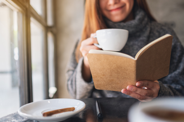 Gros plan image d'une belle femme asiatique lisant un livre tout en buvant du café dans un café  - Photo, image
