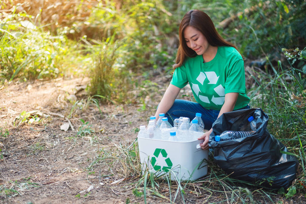 Eine schöne Asiatin sammelt Plastikflaschen für das Recycling-Konzept in einer Schachtel und einer Tüte ein - Foto, Bild