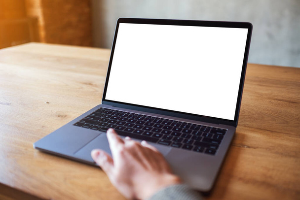 Imagen burlona de una mujer usando y tocando el panel táctil de la computadora portátil con pantalla de escritorio blanca en blanco en la mesa de madera - Foto, imagen