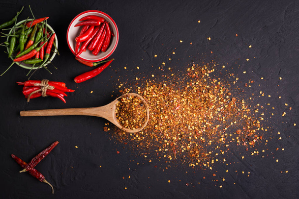 Lapos laikus összetétele, porított és nyers chili paprika a sötét háttér előtt. Hely a szöveg - Fotó, kép