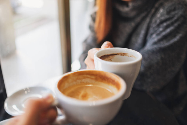 Closeup image of a woman and a man clinking coffee mugs in cafe - Photo, image