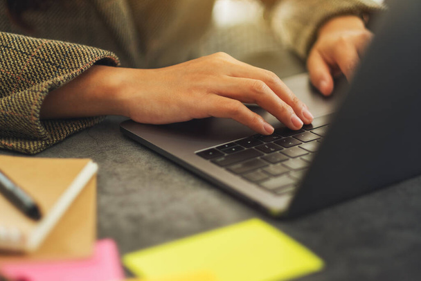 Imagem de perto de uma mulher de negócios usando e digitando no computador portátil com papelada na mesa no escritório - Foto, Imagem