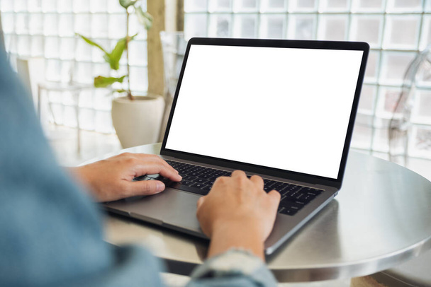 Εικόνα mockup μιας γυναίκας που χρησιμοποιεί και πληκτρολογεί σε φορητό υπολογιστή με λευκή οθόνη επιφάνειας εργασίας  - Φωτογραφία, εικόνα