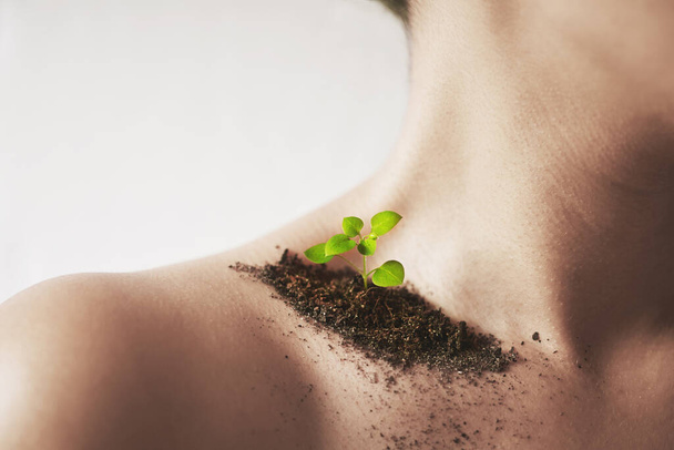 Every flower must grow through dirt. Shot of an unidentifiable young womans shoulder with soil and a small seedling on it. - Фото, изображение