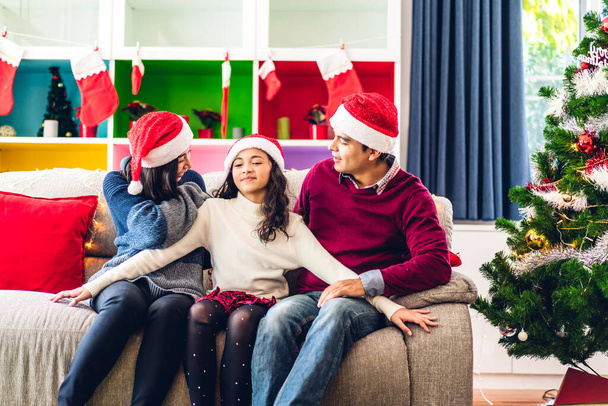 Portrait of happy asian family father and mother with daughter in santa hats having fun look at camera and enjoying spending time together in christmas time at home - Фото, изображение