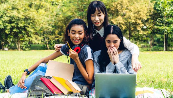 Egy csoport mosolygós nemzetközi diák vagy tinédzser ül és tanul laptoppal csinálja a házi feladatot olvasott könyvet együtt parkban egyetemen.Oktatás és barátság koncepció - Fotó, kép