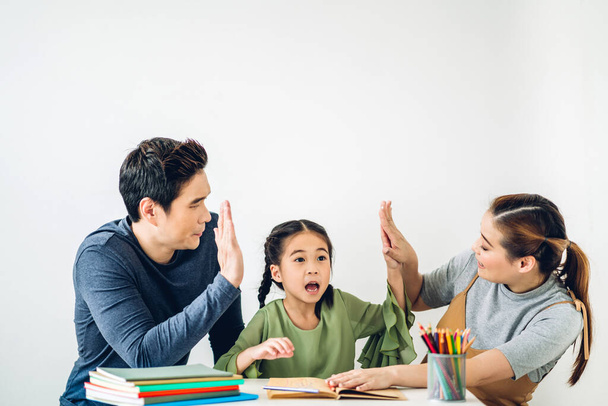 Portrait enjoy happy love asian family father and mother with little asian girl learn and study on table.Mom and dad with asian young girl writing with book and pencil making homework in homeschool at home.Education - Photo, Image