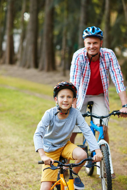 Lets ride. Portrait of a father and son riding bicycles in a park. - Photo, image