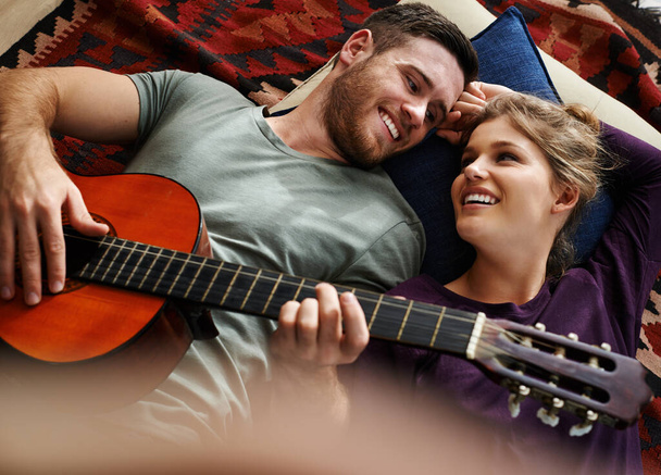 ¿Te gustó esa pequeña cancioncita? Tiro de un joven tocando la guitarra mientras yacía en el suelo con su novia. - Foto, imagen