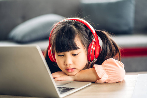 Öğrenci küçük kız öğreniyor ve dizüstü bilgisayara bakıyor ev ödevi yapıyor çevrimiçi eğitim sistemi ile bilgi öğreniyor. Evde öğretmenle çocuk video konferansı - Fotoğraf, Görsel
