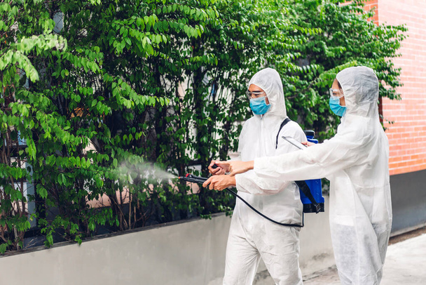 Professzionális csapatok fertőtlenítő dolgozó védő maszk és fehér ruha fertőtlenítő spray tisztító vírus, hogy segítse a szolgáltatás ölni coronavirus az ügyfél otthonában - Fotó, kép