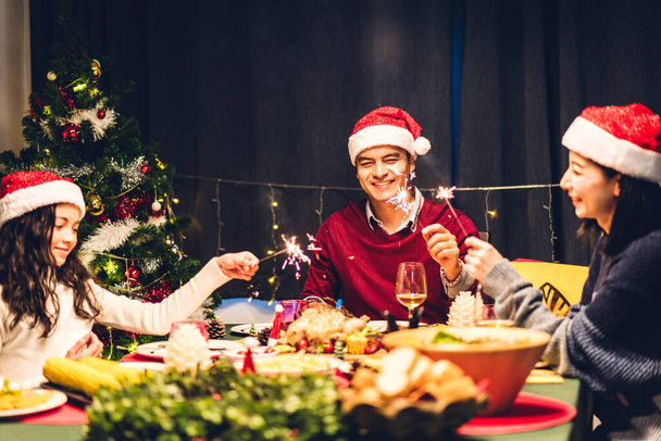 Retrato de una familia grande y feliz celebrando los sombreros de Santa Claus divirtiéndose en Acción de Gracias y comiendo comida juntos disfrutando pasar tiempo juntos en Navidad en casa - Foto, imagen