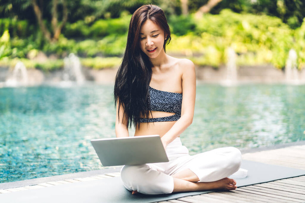 笑顔の幸せな美しさの肖像アジアのフリーランスの旅行ブロガーの女性はリゾートスパでリラックス夏の旅行休暇にスイミングプールでラップトップコンピュータの使用と仕事の技術をリラックス - 写真・画像