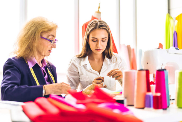 Portrait of young beautiful pretty owner business woman fashion designer stylish sitting and working.Attractive senior woman designer working with sewing machine and colorful fabrics at fashion design workshop studio - Photo, Image