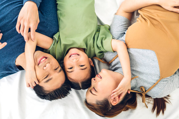 Top view of portrait enjoy happy smiling love asian family father and mother with young parent little cute asian girl looking at camera in moments good time lying on the floor at home - Fotografie, Obrázek