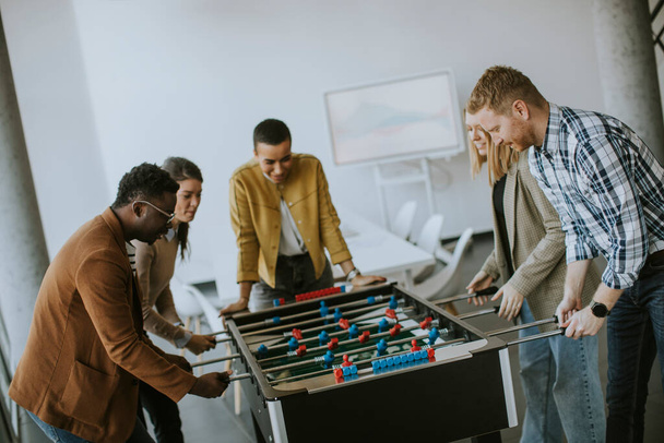 Jovem bonito casual multiétnico pessoas de negócios jogando futebol de mesa e relaxante no escritório - Foto, Imagem