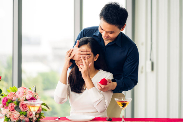 Fiatal jóképű férfi gyűrűt ad meglepetésként a barátnőjének és együtt beszélgetnek Valentin napon az étteremben. - Fotó, kép