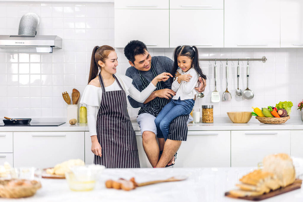 Portrait of enjoy happy love asian family father and mother with little asian girl daughter child play and having fun cooking food together with baking cookie and cake ingredient on kitchen - Foto, immagini