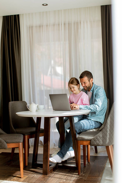 Pai e filha usando computador portátil juntos na sala - Foto, Imagem
