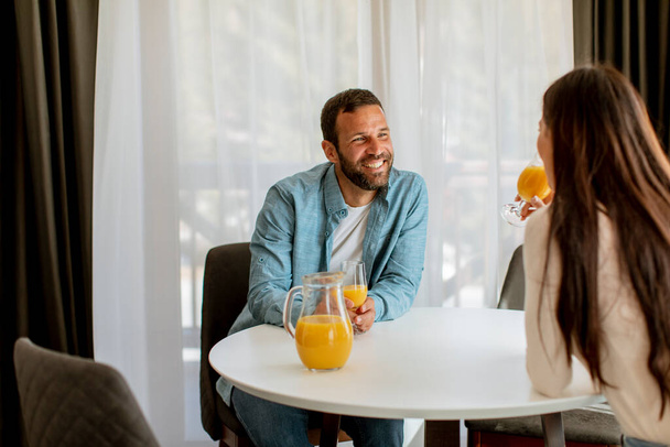 Junges Paar trinkt Orangensaft im Wohnzimmer - Foto, Bild