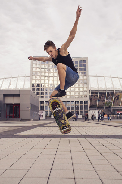 Mladá blondýna chlap skoky na skateboardu v neformálním oblečení v do u - Fotografie, Obrázek