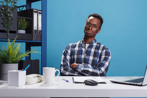 Unhappy moody young adult business company office worker with depressed face expression while in workspace. - 写真・画像