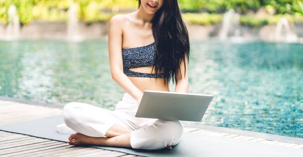 Portrait of smiling happy beauty asian freelancer traveler blogger woman relax using and work technology of laptop computer in swimming pool on summer travel vacation relaxing at resort spa - Photo, Image