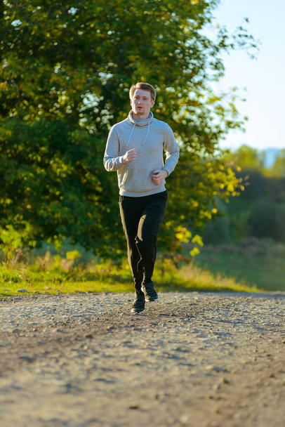 Man jogging in rural nature at beautiful summer day. Sport fitness model caucasian ethnicity training outdoor. - Foto, imagen