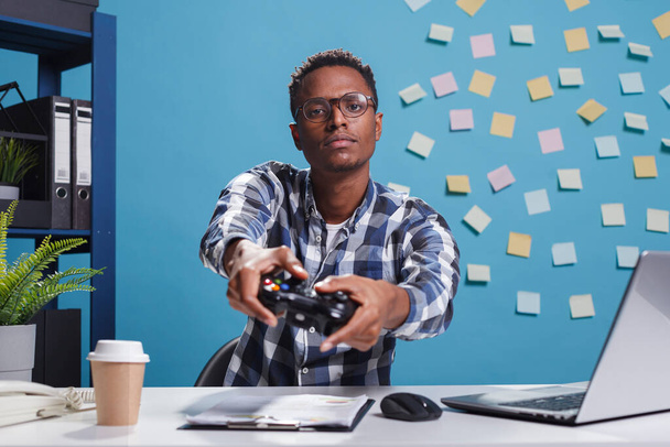 POV des selbstbewussten, wettbewerbsfähigen Spielers, der Freizeitaktivität genießt, während er Videospiele bei der Arbeit spielt. - Foto, Bild