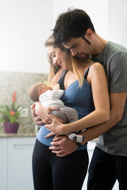 Mother breastfeeding her son in the kitchen with his father by her side - Φωτογραφία, εικόνα