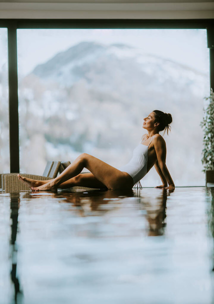 Ładna młoda kobieta relaksująca się na basenie bezkresnym w zimie - Zdjęcie, obraz