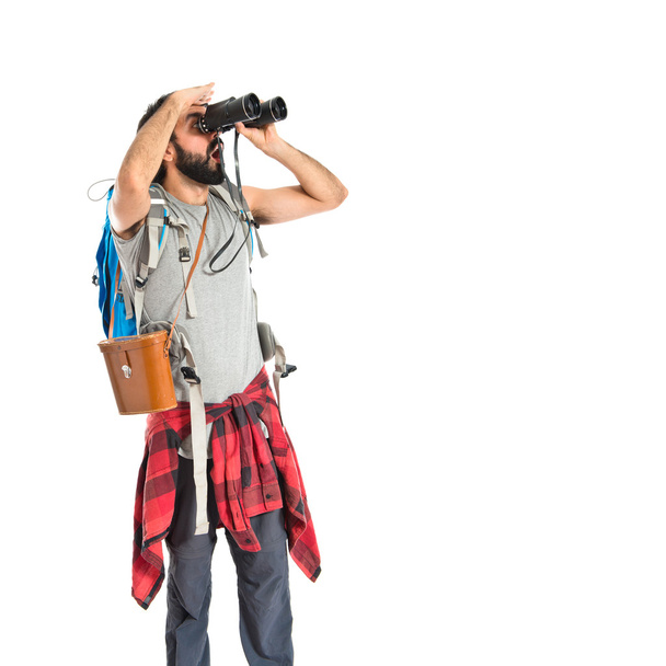 Backpacker with binoculars over isolated white background - Photo, image