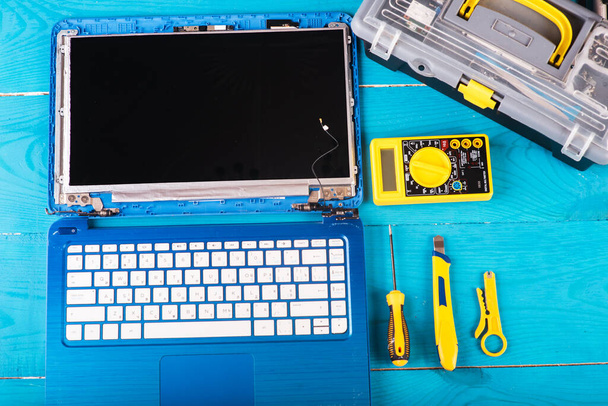 Wizard répare l'ordinateur portable avec des outils et des mains sur la table bleue. vue de dessus - Photo, image