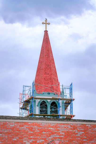 Pod budową kościelnej wieży przeciw zachmurzonemu niebu w Dolinie Krzemowej, San Jose, CA. Struktura kościoła z czerwonymi cegłami na ścianie i betonowymi płytkami na wieży. - Zdjęcie, obraz
