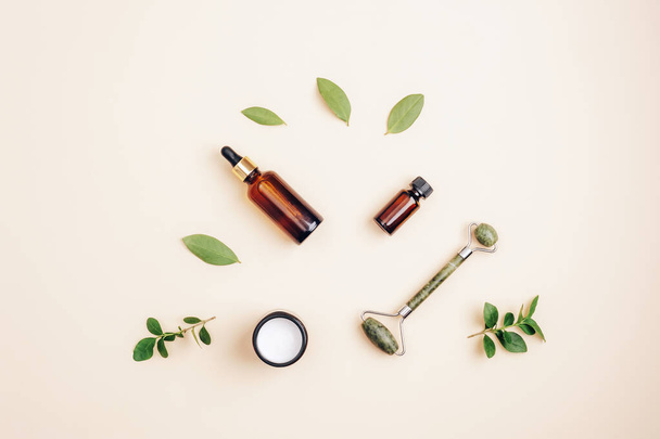 Modern apothecary, natural ingredients. Cosmetic serum, cream, facial roller and essential oil. Top view, flat lay. - 写真・画像