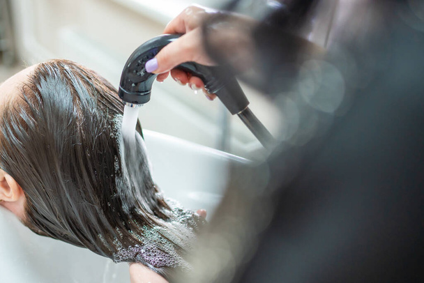 Close up view of washing hair in sink in beauty salon - 写真・画像