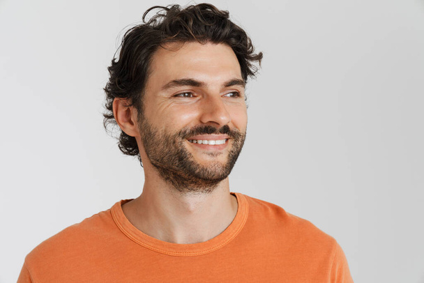 Jeune homme brune avec soies souriantes et regardant de côté isolé sur fond blanc - Photo, image