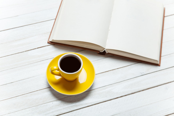 Book and cup of coffee on wooden table. - Photo, image
