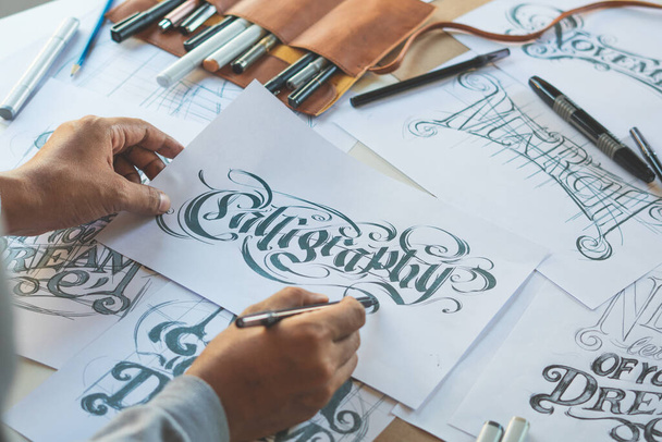 Typografie Kalligraphie Künstler Designer Zeichnung Skizze schreibt lassen Schreibfeder Pinsel Tinte Papier Tischvorlage artwork.Workplace Design Studio. - Foto, Bild