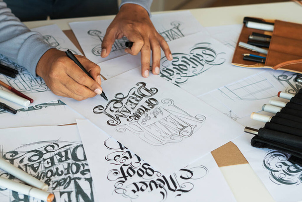 Typography Calligraphy artist designer drawing sketch writes letting spelled pen brush ink paper table artwork.Workplace design studio. - Fotó, kép