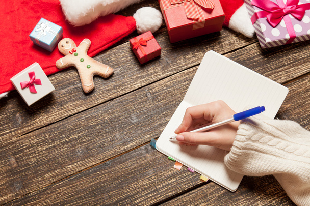 Kadın defter yakınındaki Noel hediyeleri için istek listesi yazma - Fotoğraf, Görsel