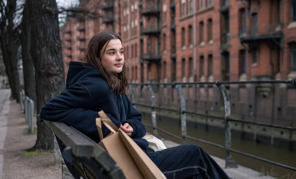 Une jeune femme assise sur un banc avec un paquet, le concept de shopping. - Photo, image