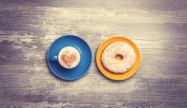 Tasse Kaffee und Donut auf einem Tisch. - Foto, Bild