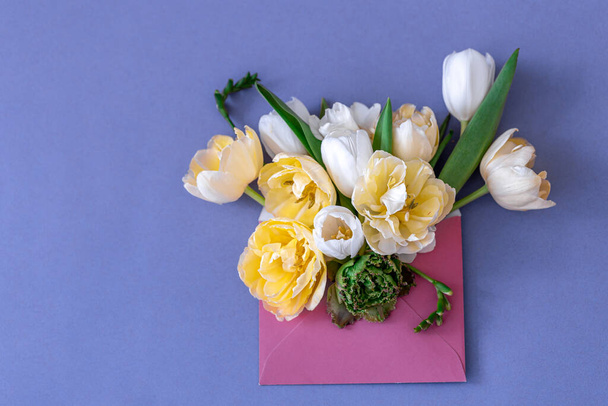 Bloemen in een envelop op een gekleurde achtergrond, plat gelegd. - Foto, afbeelding