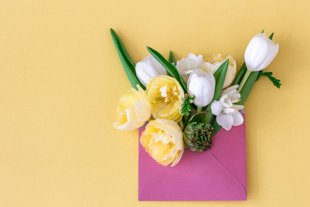 Flowers in an envelope on a colored background, flat lay. - Фото, изображение