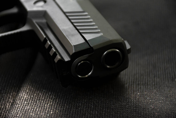 Automatic 9mm pistol gun muzzle on black leather background, soft and selective focus. - Valokuva, kuva
