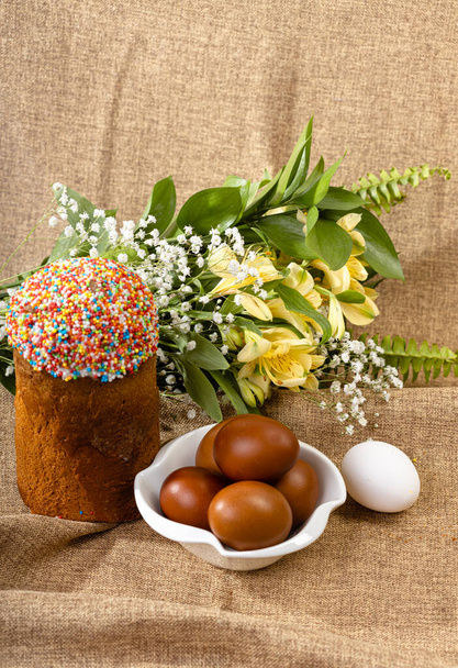 Wielkanocna kompozycja ciasta wielkanocnego, malowanych jaj i wiosennych kwiatów na tle koronki. - Zdjęcie, obraz