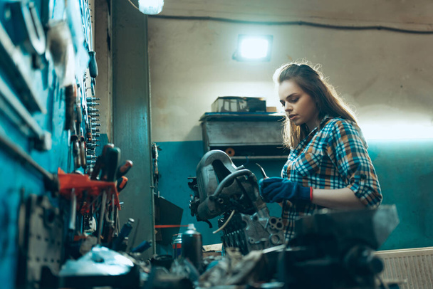 Destroying gender stereotypes. Young woman auto mechanic working at auto service station using different work tools. Gender equality. Work, occupation, car - Photo, image