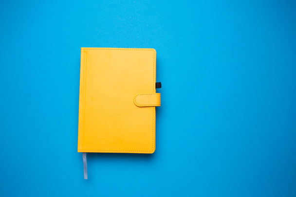 Diary of yellow color on a blue isolated background close-up - Foto, afbeelding