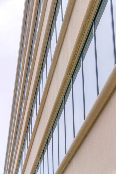 Widok boczny budynku z beżowymi i szklanymi oknami w Dolinie Krzemowej, San Jose, Kalifornia. Zewnątrz budynku z betonowymi okładzinami ściennymi i szklanymi oknami. - Zdjęcie, obraz
